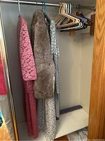Three dresses and one fur jacket hung in closet on hangers showing overall lot content.