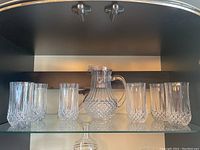 Full set showing one crystal water pitcher and six matching water glasses with diamond-cut pattern on lower half and vertical ridges on upper half.