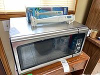 Danby microwave with Braun hand blender on top shown from an angle, stainless steel finish visible