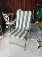 Green and beige striped foldable patio chair with metal frame, showing fabric and structure condition.