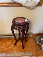 Front view of the wood frame plant stand showing curved legs, carved side details, and stone center on top.
