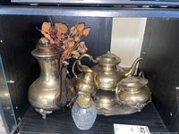 Matching coffee pot, teapot, creamer, sugar bowl on silver tray with dried flowers in glass vase and a glass crystal lighter