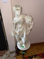 Full view of the white classical-style statue on wooden stand showing entire statue and pedestal