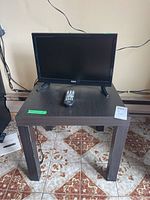 RCA 19-inch TV on black wood-look TV stand with remote control on stand