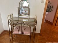 Photo showing the metal vanity table with smoked glass top and tilting mirror, along with matching upholstered chair.