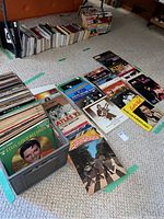 Milk crate filled with Elvis Presley records and stacks of other albums in front of bookshelves