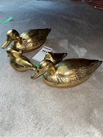 Four brass ducks on carpet showing sizes and overall condition