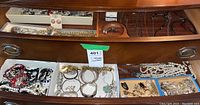 Open wooden drawer showing trays and boxes filled with assorted jewelry