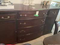 Front view of dark wood sideboard buffet showing curved drawers and brass handles