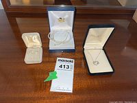 Full lot overview showing three sets of jewelry in boxes: white gold heart pendant necklace, freshwater pearl bracelet and earrings, pearl-like clip-on earrings.