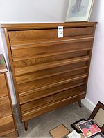 Front view of wooden dresser showing four drawers and tapered legs.