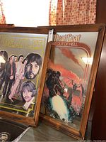 Two wood framed mirrors side by side, showing the Beatles mirror on the left and Meatloaf mirror on the right with clear imprinted artwork and polished wood frames.