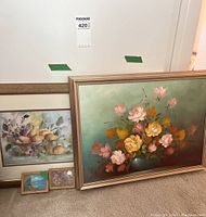 Large floral painting with yellow and pink flowers in green vase, gold frame, leaning against wall