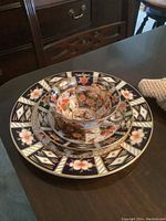 Porcelain cup, saucer, and luncheon plate stacked showing detailed Imari pattern in cobalt blue, red, gold and floral motifs.