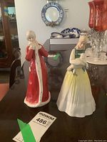 Two Royal Doulton figurines, Springtime and Wintertime, shown side by side on a reflective surface.