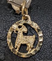Close-up front view of 10K yellow gold ram pendant showing detailed texture on ram and circular border.