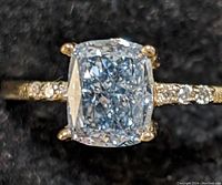 Front-facing view of ring showing cushion-cut blue center diamond and accent stones