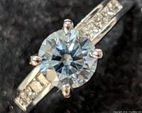 Close-up top view showing round brilliant center stone and channel-set shoulder accents.