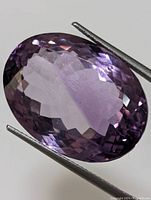 Close-up of the oval faceted amethyst gemstone showing the purple color and facet arrangement.