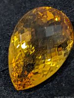 Close-up angled photo of the pear-shaped citrine gemstone showing its checkerboard facets and color.