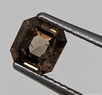 Front view of octagonal emerald-cut brown diamond held in tweezers
