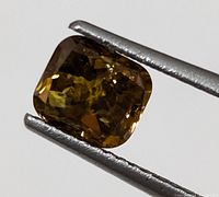 Front view of cushion-cut orange diamond held in tweezers