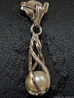 Close-up photo of silver pendant front with freshwater pearl inside twisted silver cage