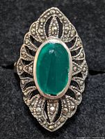 Close-up front view of sterling silver ring showing oval green onyx center and surrounding marcasite stones in detailed filigree
