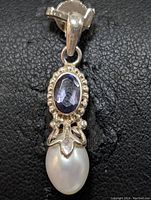 Close-up front view of the sterling silver pendant showing the oval iolite gemstone and the drop-shaped freshwater pearl with decorative silver setting.