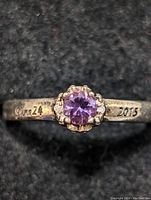 Close-up photo of the sterling silver ring with round purple amethyst stone and date engraving.