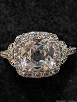 Close-up front view of the sterling silver ring showing the large square-cut cubic zirconia center stone surrounded by smaller round stones in a halo setting.