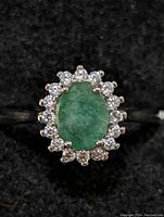 Clear top view of sterling silver ring with green oval emerald gemstone and surrounding clear cubic zirconia stones.