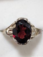 Top view of the sterling silver ring showing the deep red oval garnet gemstone and the textured silver design on the band.