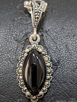 Close-up front view of the pendant showing the marquise-shaped black onyx center stone surrounded by marcasite stones.