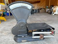 Side angle view of the antique scale showing the large dial, weighing platform and sliding weights details.