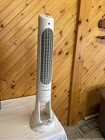 Front view of Honeywell tower fan showing tall white body, vertical vent grille, and round base with wrapped power cord.