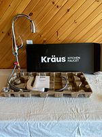 Kraus kitchen faucet, unopened in black box with components and manual displayed in molded paper pulp packaging.