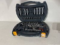Open ratchet set in black plastic carrying case showing ratchets, sockets, wrenches, and accessories spread inside.