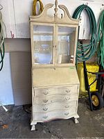 Front view of the farmhouse rustic secretary desk showing the bowed drawers, glass door cabinet on top, and drop front writing surface.