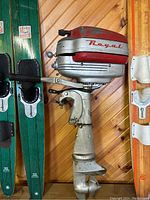 Full vertical view of the outboard motor showing the red and silver casing, propeller, and mounting clamp.