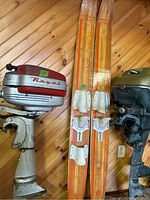 Photo showing two vintage wooden water skis with white bindings, identified as Mastercraft Aqua Rite, alongside vintage boat motors.