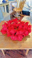 Red poinsettia wreath on wooden table in room setting.