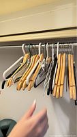 Photo showing a range of clothing hangers on a closet rod, including wooden, plastic, metal, and padded fabric hangers.