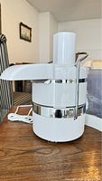 Side view of the Jack LaLanne Power Juicer showing feeding chute, locking arm, and white and chrome finish.