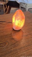 The salt lamp lit with a warm yellow glow to show illumination and texture of salt crystal.