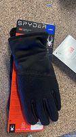 Close-up photo of one Spyder glove showing textured grip and attached brand tags.