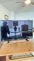 Front view of the 32-inch Roku TV on wooden table showing the screen and reflections in daylight