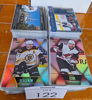 Stack of hockey cards showing Patrice Bergeron and Max Domi holographic base cards with other insert cards visible in stacks behind them.