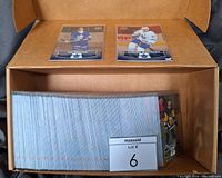 Box of over 200 hockey cards stacked and arranged horizontally showing card edges in storage box