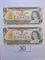 Front view of two uncirculated Canadian one dollar bills showing Queen Elizabeth II and serial numbers BA85474253 U